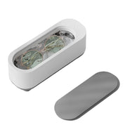 Dispositivo pulizia occhiali ad ultrasuoni bianco, coperchio grigio, design moderno, ideale per lenti e gioielli, tecnologia avanzata, compatto ed efficiente.
