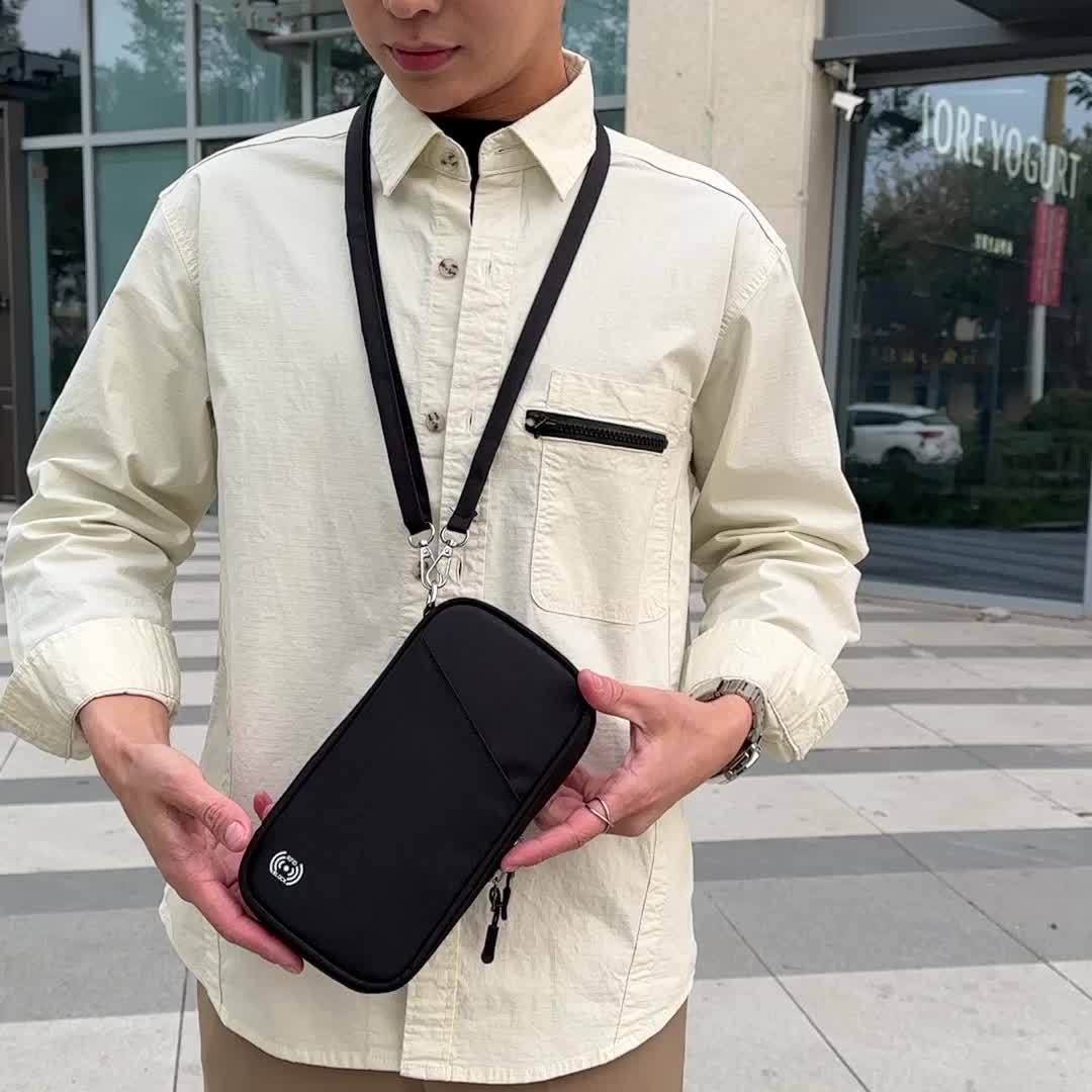 Uomo con camicia beige indossa borsa a tracolla nera, tasca frontale con zip, all'aperto. Accessorio moda uomo, stile urbano casual.