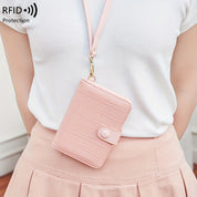 Portafoglio rosa con protezione RFID, design a coccodrillo, indossato a tracolla. Accessorio moda donna, elegante e sicuro per carte e contanti.