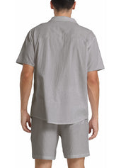 Uomo in completo estivo grigio chiaro, camicia a maniche corte e pantaloncini coordinati, vista posteriore. Abbigliamento casual estivo maschile.