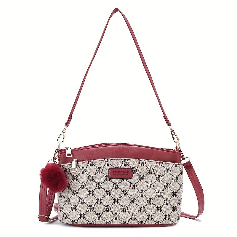 Borsa a tracolla elegante in pelle rossa e tessuto stampato, con ciondolo pompon. Design moderno, ideale per moda donna e accessori di tendenza.