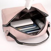 Borsa da viaggio rosa aperta, mostra power bank, libri e cosmetici all'interno. Design elegante, ideale per organizzare accessori essenziali.