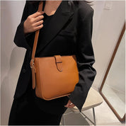 Borsa a tracolla in pelle marrone indossata da una donna con giacca nera. Elegante accessorio moda, perfetto per look casual e formali.