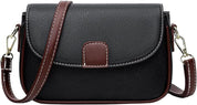 Borsa a tracolla in pelle nera con dettagli marroni, chiusura a patta, cuciture bianche, tracolla regolabile, elegante e versatile per donna.