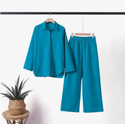 Completo donna turchese, camicia a maniche lunghe e pantaloni larghi, appesi su gruccia. Moda elegante, abbigliamento casual, tessuto leggero.