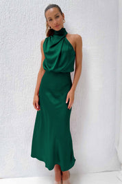 Abito lungo verde smeraldo elegante, senza maniche, con collo alto drappeggiato, indossato da una donna. Perfetto per eventi formali e serate.
