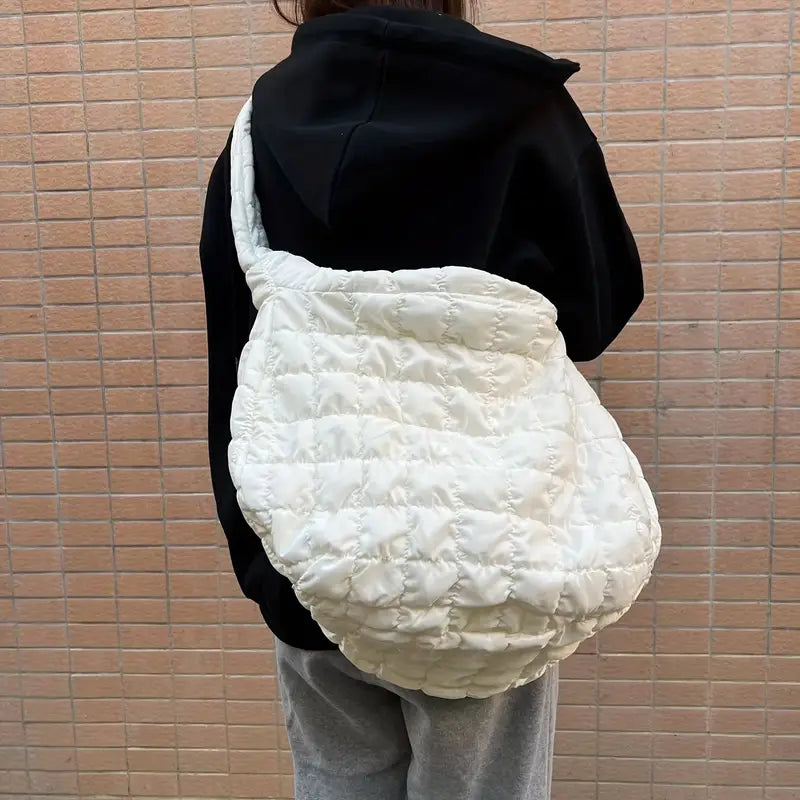 Zaino trapuntato bianco su persona con felpa nera e pantaloni grigi, design moderno e spazioso, ideale per moda urbana e casual.