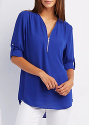 Blusa donna blu elettrico con zip frontale, maniche a 3/4 arrotolate, abbinata a pantaloni bianchi. Moda casual elegante, abbigliamento femminile.