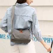 Donna con camicia di jeans e borsa a tracolla grigia in tessuto, design casual e moderno, ideale per uso quotidiano e moda urbana.