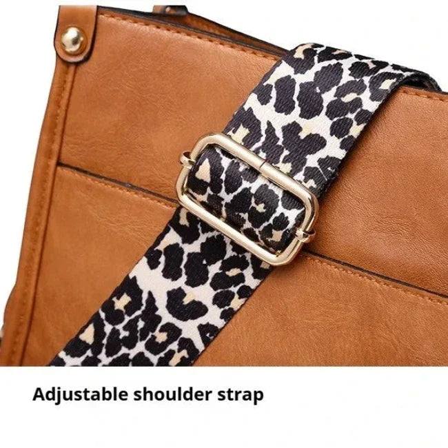 Cinturino regolabile a spalla in pelle marrone con fibbia dorata e motivo leopardato. Accessorio moda elegante e versatile.