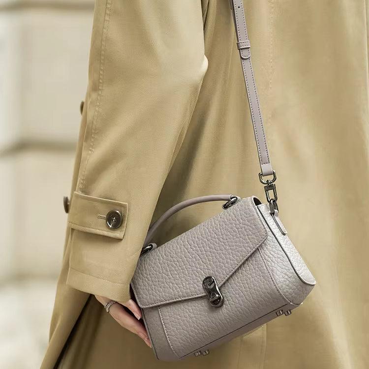 Cappotto beige con borsa a tracolla in pelle grigia, design elegante, chiusura a scatto, moda autunnale, accessorio di tendenza per donna.