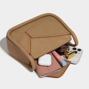 Borsa a tracolla beige in pelle con oggetti: smartphone, rossetto, profumo, AirPods, portafoglio. Design elegante e moderno. Accessori moda donna.