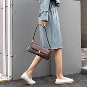 Donna con trench azzurro e borsa a tracolla marrone, scarpe espadrillas bianche. Moda femminile elegante, accessori di tendenza.