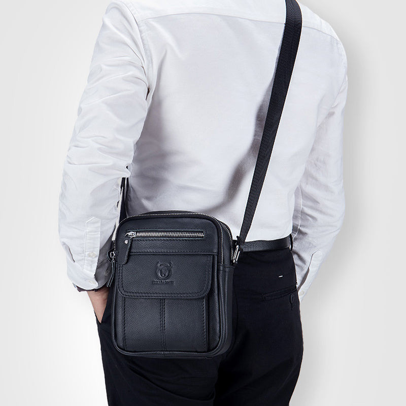 Uomo con borsa a tracolla in pelle nera, elegante e pratica, con zip e tasche multiple. Ideale per lavoro e viaggi. Accessorio moda maschile.