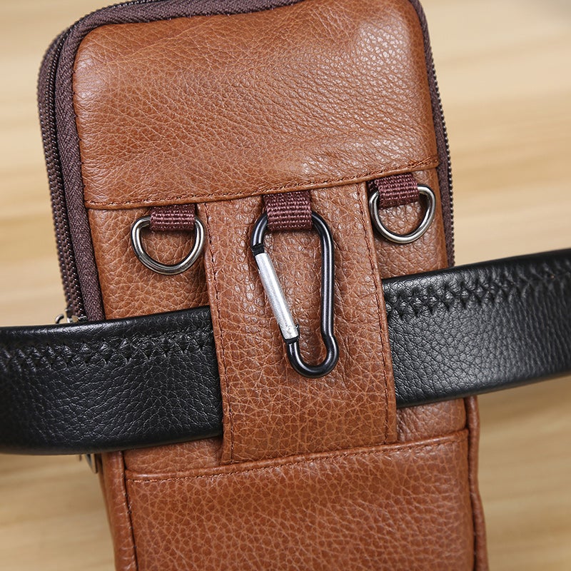 Marsupio in pelle marrone con moschettone e cintura nera, design elegante e pratico, ideale per viaggi e uso quotidiano. Accessorio moda uomo.