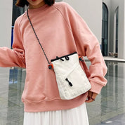Donna con felpa rosa e borsa a tracolla bianca, design casual, moda urbana, abbigliamento autunnale, stile moderno, shopping online.