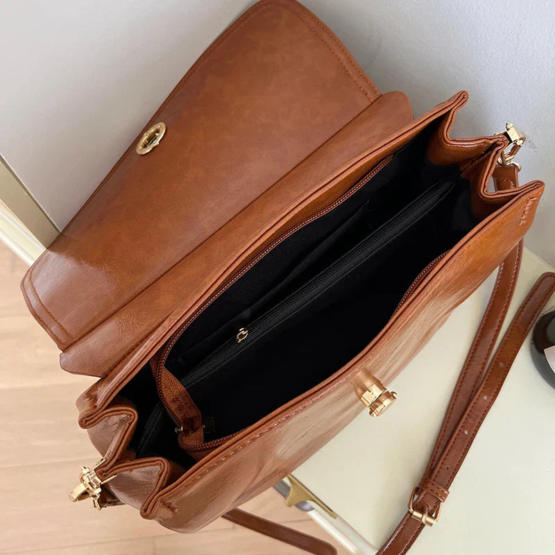 Borsa a tracolla in pelle marrone con chiusura dorata, scomparti interni spaziosi e tracolla regolabile. Elegante accessorio moda donna.