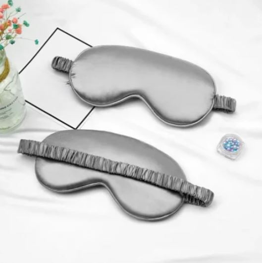 Maschera per dormire in seta grigia su sfondo bianco, con elastico arricciato. Accessorio relax, ideale per migliorare il sonno e ridurre la luce.