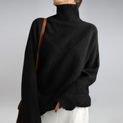 Maglione nero a collo alto in maglia, design a rombi, indossato da una donna. Elegante e caldo, perfetto per l'inverno. Moda femminile casual.
