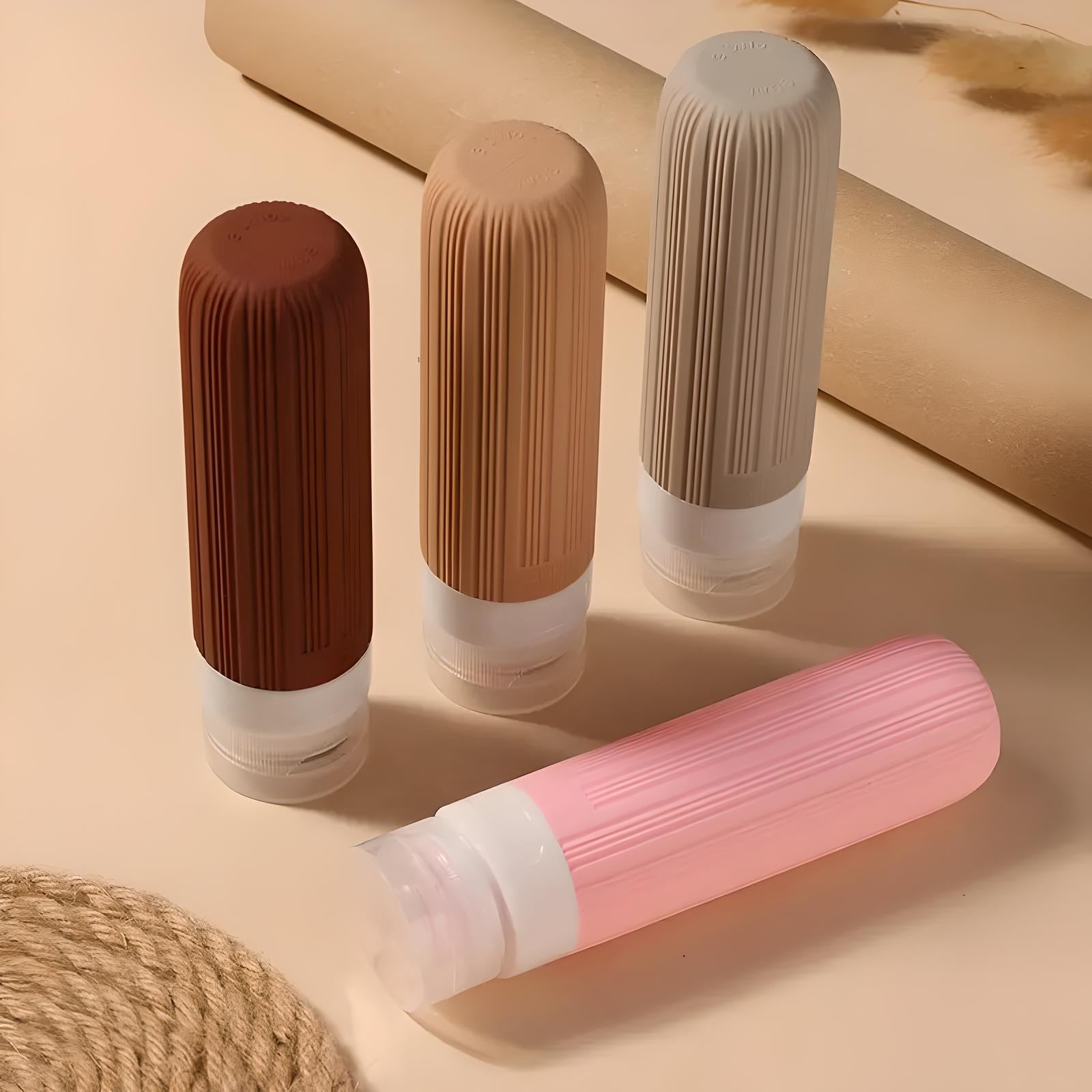 Quattro flaconi da viaggio in silicone colorati su sfondo beige, ideali per cosmetici e liquidi. Design compatto e riutilizzabile.