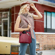Donna con borsa a tracolla rossa in pelle, indossa cappello marrone e camicia a quadri, posa accanto a un'auto vintage. Moda autunnale elegante.