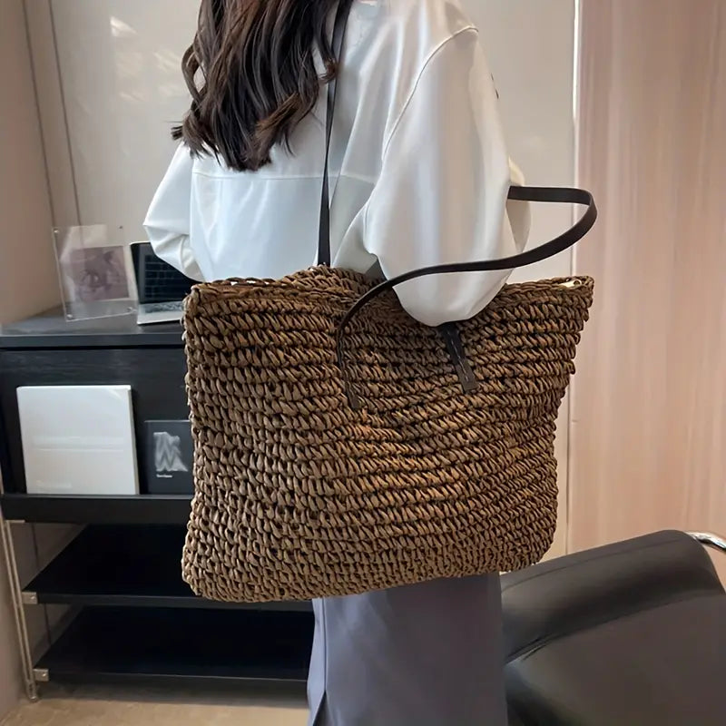 Donna con borsa a tracolla in paglia marrone, indossa camicia bianca e gonna grigia. Accessorio moda estivo, stile casual ed elegante.
