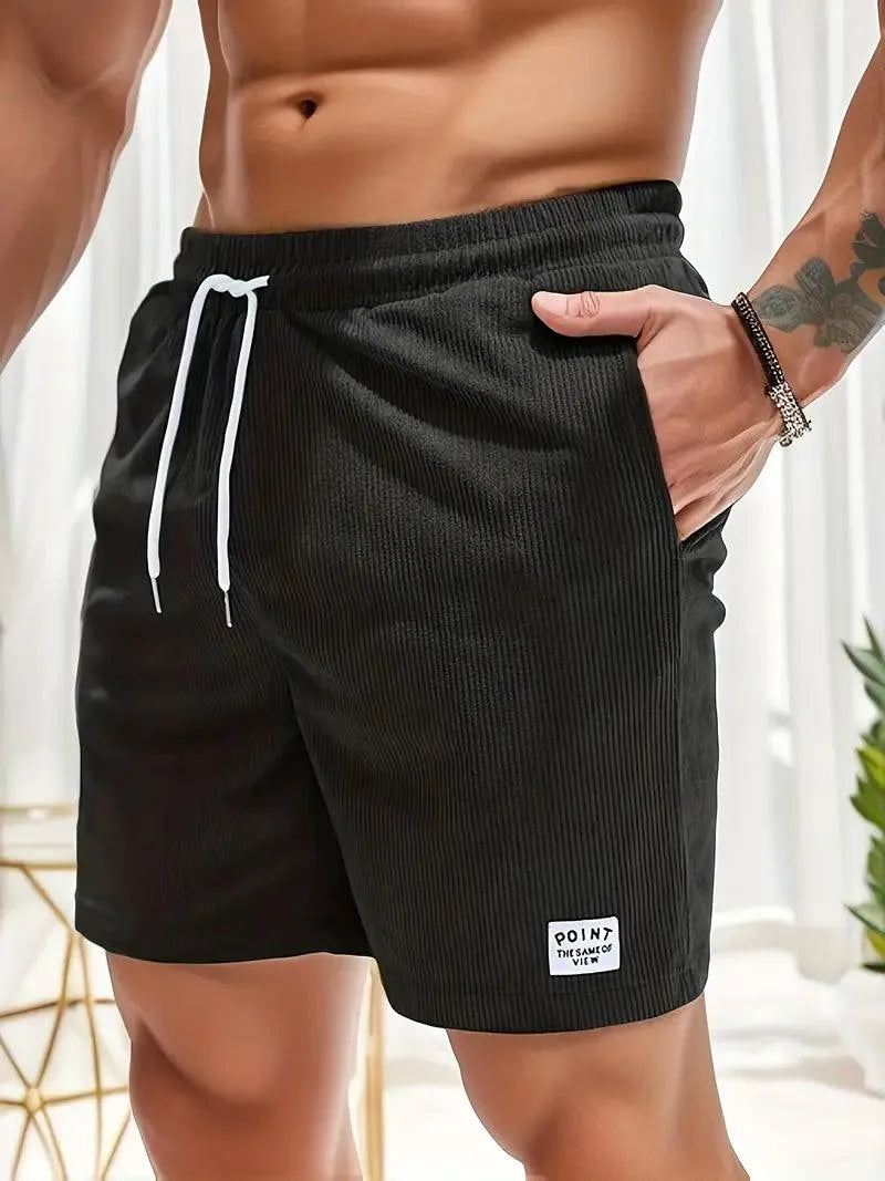 Pantaloncini da uomo neri a coste, con coulisse bianca e tasche laterali. Ideali per palestra e casual. Tessuto comodo e traspirante.