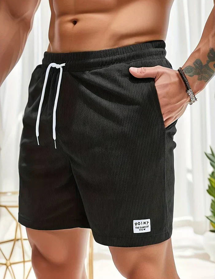 Shorts da uomo neri, tessuto a coste, con laccio bianco in vita. Design casual, ideale per l'estate. Tasche laterali, etichetta "Point" visibile.