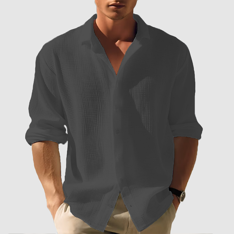 Camicia uomo nera a maniche lunghe, tessuto leggero, stile casual, abbinata a pantaloni chiari. Ideale per moda maschile estiva.