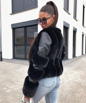 Donna con giacca in pelliccia sintetica nera, occhiali da sole, jeans attillati, capelli raccolti, posa all'aperto. Moda autunnale, stile urbano.