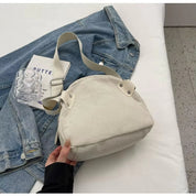 Borsa a tracolla bianca in tessuto a coste su giacca di jeans, con bicchiere trasparente. Accessorio moda casual, stile urbano, donna.