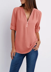 Blusa donna rosa con scollo a V e zip, maniche a 3/4 arrotolate, abbinata a jeans blu. Moda casual elegante, abbigliamento femminile trendy.