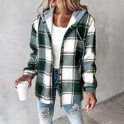 Giacca a quadri verde e bianca con cappuccio, indossata su maglia bianca e jeans strappati. Donna con capelli biondi, tiene bicchiere di caffè.