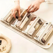 Mani organizzano cosmetici in pochette trasparenti su vassoio bianco. Accessori trucco, borse da viaggio, organizzazione beauty.