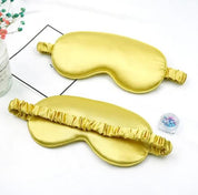 Mascherine per dormire in seta dorata su sfondo bianco, con elastico arricciato. Accessori per il sonno, eleganti e confortevoli.