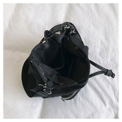 Borsa a tracolla nera aperta su letto bianco, design elegante con cerniera e tasche interne, ideale per moda donna e accessori quotidiani.