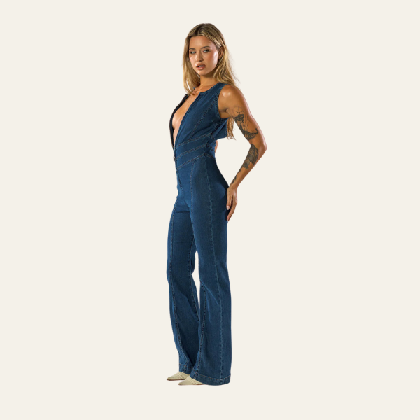 Donna in tuta jeans blu scuro con scollo profondo e dettagli cut-out, posa laterale. Abbigliamento moda femminile, stile casual chic.