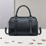 Borsa a mano in pelle nera su sfondo neutro, design elegante con manici e tracolla regolabile. Accessorio moda donna, stile classico.