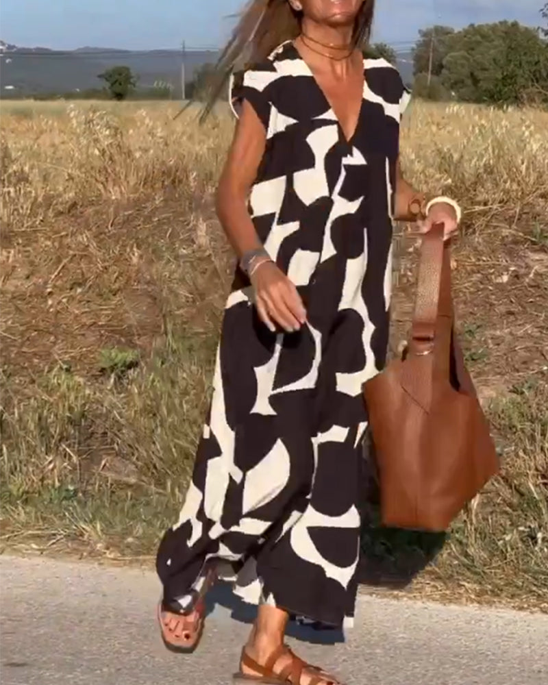 Abito lungo estivo donna con motivo astratto bianco e nero, borsa in pelle marrone, sandali marroni, sfondo campagna. Moda casual elegante.