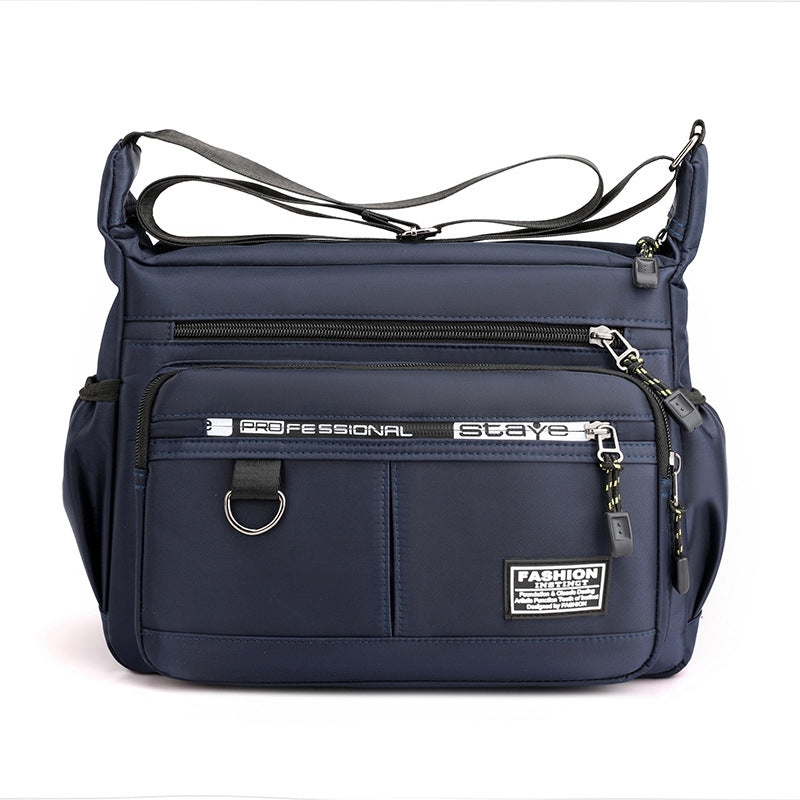 Borsa a tracolla blu scuro con tasche multiple, cerniere e dettagli in metallo. Design moderno, ideale per viaggi e uso quotidiano.