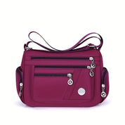 Borsa a tracolla viola con tasche multiple e cerniere, design elegante e pratico, perfetta per uso quotidiano e viaggi. Accessorio moda donna.