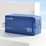 Borsa da toilette blu impermeabile con cerniera, design moderno, ideale per viaggi. Scritta "Have a Good Trip" e numero "01" visibili.