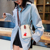 Donna con camicia azzurra oversize, pantaloncini neri e borsa a tracolla bianca con stampa. Stile casual chic, moda femminile contemporanea.