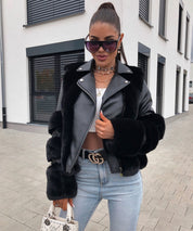 Donna con giacca in pelle nera e pelliccia, occhiali da sole oversize, jeans attillati e borsa bianca. Look moda autunnale urbano elegante.