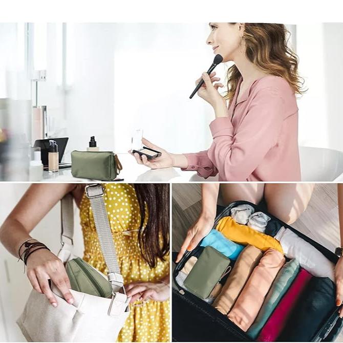 Donna che applica trucco con pennello, borsa cosmetica verde su tavolo, borsa a tracolla con tasca, organizzatore da viaggio con vestiti colorati.