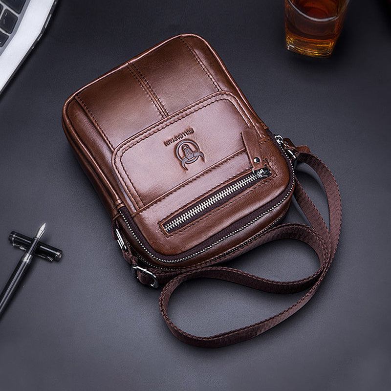 Borsa a tracolla in pelle marrone, design elegante con cerniera frontale e logo, ideale per uomo, accessorio moda, stile casual e pratico.