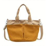 Borsa tote in tela gialla con manici beige, tracolla regolabile e tasche frontali. Design casual, ideale per shopping e uso quotidiano.