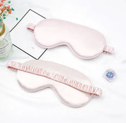 Mascherine per dormire in seta rosa su sfondo bianco, con elastico arricciato. Accessorio per il sonno, relax, benessere.