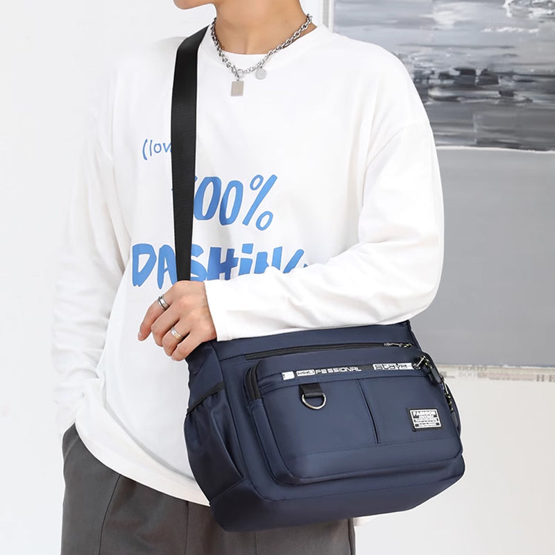 Borsa a tracolla blu unisex, design moderno, indossata su maglia bianca con scritta blu. Accessorio moda casual, ideale per uso quotidiano.