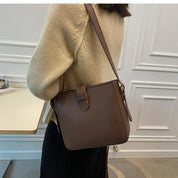Borsa a tracolla marrone in pelle, indossata da una donna con maglione beige. Design elegante, ideale per moda autunnale e invernale.